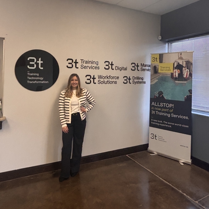 Bid writer Danielle standing against a wall with 3t branding