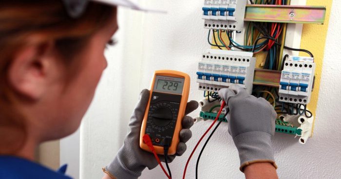 Person using a multimeter to test voltage in an electrical panel.