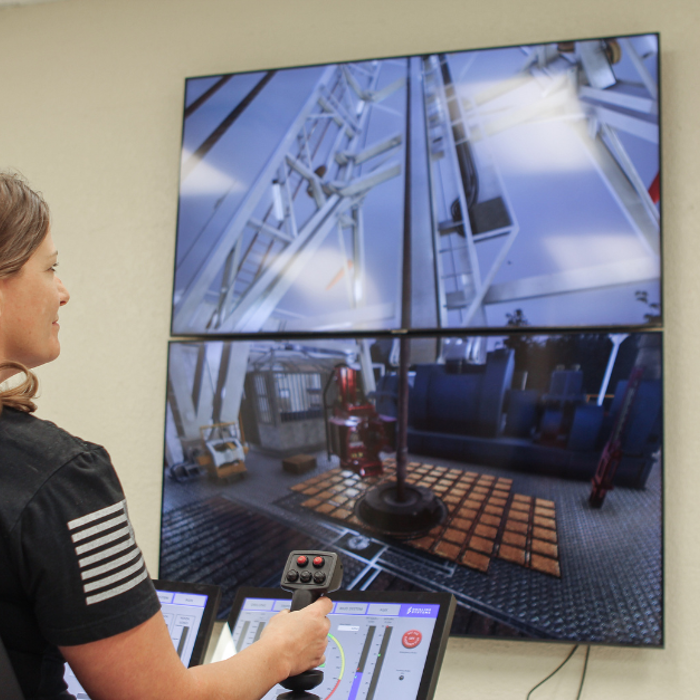 A person operates a control system with screens displaying drilling operations.